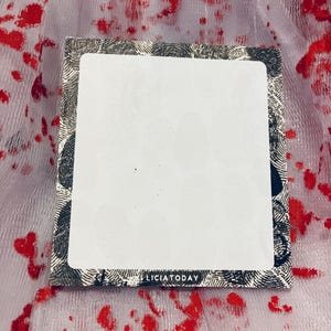 May include: A white notepad with a black border featuring a fingerprint pattern. The notepad has the text "Licia Today" printed on the bottom.