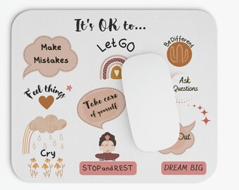 May include: A white mouse pad with the text "It's OK to..." and a list of phrases including "Make Mistakes", "Let Go", "Feel Things", "Take Care of Yourself", "Cry", "Be Different", "Ask Questions", "Dream Big", and "Stop and Rest". The phrases are surrounded by illustrations of hearts, rainbows, clouds, cacti, and a woman meditating.