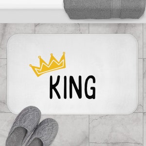 Puede incluir: Alfombra de baño blanca con una corona amarilla y la palabra "KING" en letras negras.