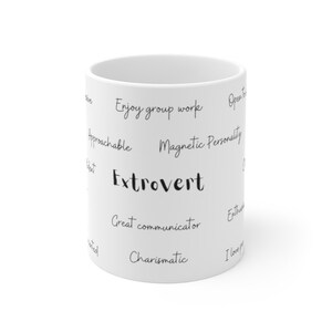 Op de afbeelding: Een witte keramische mok met zwarte tekst die "Extrovert" zegt en een lijst met persoonlijkheidstrekken die geassocieerd worden met extraversie, waaronder "Geniet van groepswerk", "Magnetische persoonlijkheid", "Uitstekende communicator" en "Charismatisch".
