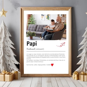 Może przedstawiać: Oprawiony wydruk z napisem "Papi" i zdjęciem dziadka i dziecka czytających. Wydruk jest w drewnianej ramie, z dekoracjami świątecznymi po bokach.