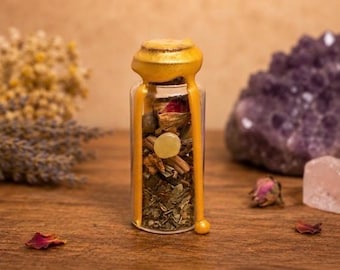 May include: A clear glass vial filled with dried herbs, flower petals, and a small yellow stone. The top is sealed with a cork and covered in dripping yellow wax that runs down the sides of the bottle, ending in a small rounded bead at the base.