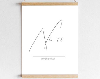 Peut inclure: Une impression en noir et blanc d'une ligne d'art représentant une chaîne de montagnes avec le texte "No. 22 Baker Street" en dessous. L'impression est encadrée dans un cadre en bois clair et accrochée à un mur blanc.