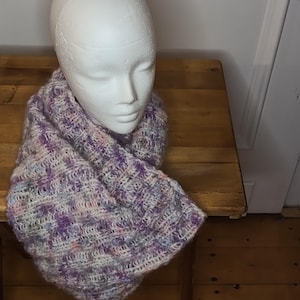 May include: A soft, purple, pink, and white knitted infinity scarf. The scarf is draped over a white mannequin head.