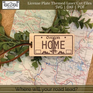 May include: A wooden license plate style sign with the text "Oregon Home" and a pine tree graphic. The sign is brown with a light wood grain. The sign is on a map of the state of Oregon.