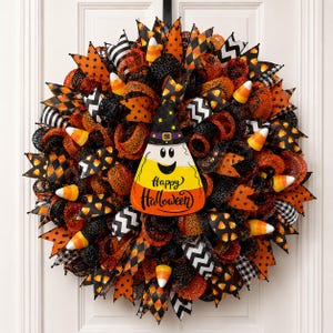 May include: A festive Halloween wreath with orange, black, and white ribbons, mesh, and candy corn accents. A candy corn-shaped sign in the center reads "Happy Halloween". The wreath is decorated with a witch hat and various patterns.