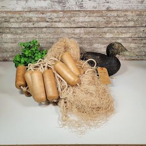 Op de afbeelding: Een bruine houten eendenlokvogel met een zwarte kop en een bruin visnet met houten drijvers. Het net heeft een label met de tekst "Gill Net" met een beschrijving van het net.