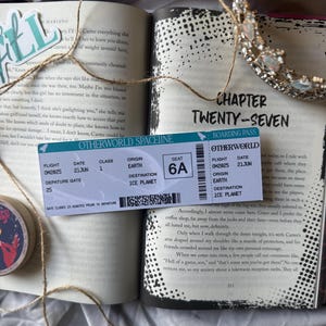 May include: An open book displaying Chapter Twenty-Seven, with a boarding pass for "Otherworld Spaceline" to "Ice Planet." A decorative crown and twine are also visible.