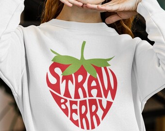 Peut inclure: Sweat-shirt blanc avec un graphique de fraise rouge. Le mot "STRAWBERRY" est écrit à l'intérieur de la forme de la fraise.