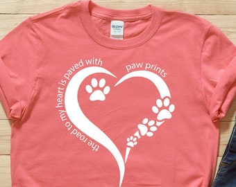 Może przedstawiać: Różowy t-shirt z białym wzorem serca. Serce składa się z odcisków łap i tekstu "The road to my heart is paved with paw prints".