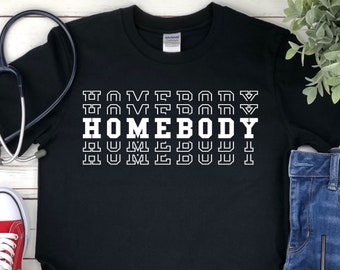 May include: Black t-shirt with the text "HOMEBODY" repeated in a stacked, retro-style font in white.