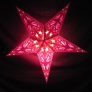 May include: A red paper star lantern with a white and yellow patterned design. The lantern is lit from the inside, creating a warm glow.