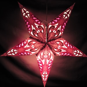May include: A pink paper star lantern with a white and pink intricate design. The lantern is lit and glowing.