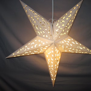 May include: A white paper star lantern with a crescent moon and star cut-out design. The lantern is lit from within, casting a warm glow.