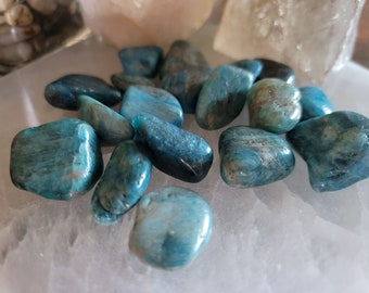 May include: A collection of teal blue tumbled stones. The stones are smooth and polished, with a variety of shapes and sizes.
