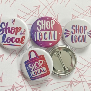 Peut inclure: Quatre boutons ronds avec le texte "Shop Local" dans différentes couleurs et styles. Les boutons sont sur un fond blanc avec des flèches roses dessinées dessus.
