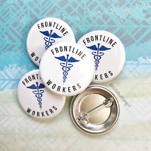 May include: Four white round buttons with a blue medical symbol and the text "FRONTLINE WORKERS" and one silver button with a pin on the back.
