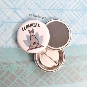 Op de afbeelding: Een witte knop met een lama die een hoofdband draagt en in lotushouding zit. De lama mediteert en de knop zegt "LLAMASTE".