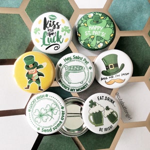 Peut inclure: Ensemble de badges sur le thème de la Saint-Patrick avec divers motifs. Les badges présentent des phrases telles que « Kiss me for Luck », « Happy St. Pat's » et « Eat, Drink, Be Irish ». D'autres motifs incluent un lutin, un pot d'or et des trèfles.