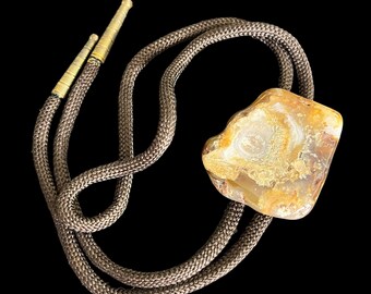 Può includere: Un cravattino bolo in pelle marrone con un grande ciondolo in agata marrone chiaro di forma irregolare.