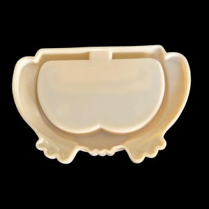 K&ouml;nnte beinhalten: Eine wei&szlig;e Plastik-Schmuckschatulle im Vintage-Stil mit einem dekorativen Design und dem Schriftzug "Made in" auf der Unterseite.