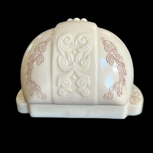 K&ouml;nnte beinhalten: Eine wei&szlig;e Keramik-Ringbox mit einem dekorativen Design. Die Box hat einen gew&ouml;lbten Deckel mit einem erhabenen Blumenmuster und einen rechteckigen Boden.
