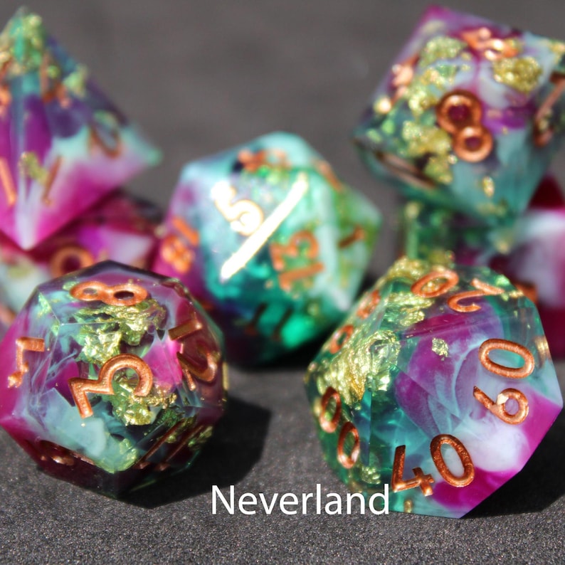 Beautiful blue, purple and green resin dice sit on a black felt table top. Light shines down on the dice making the colours swirl into a maelstrom of beautiful colour. The dice include multicoloured foils that sparkle, shimmer and dance in the light.
