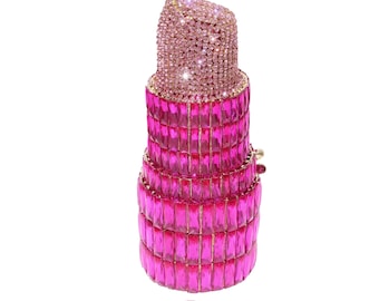 May include: A pink lipstick-shaped clutch purse covered in rhinestones. The purse is made of clear plastic and has a gold metal clasp.