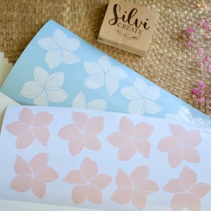 May include: Two sheets of floral stickers. One sheet is light blue with white flower designs. The other sheet is white with peach-colored flower designs. A wooden block with the text "Silvi Create" is in the background.
