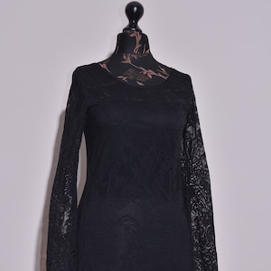 May include: A black lace dress with long sleeves and a scalloped hemline. The dress is on a mannequin.