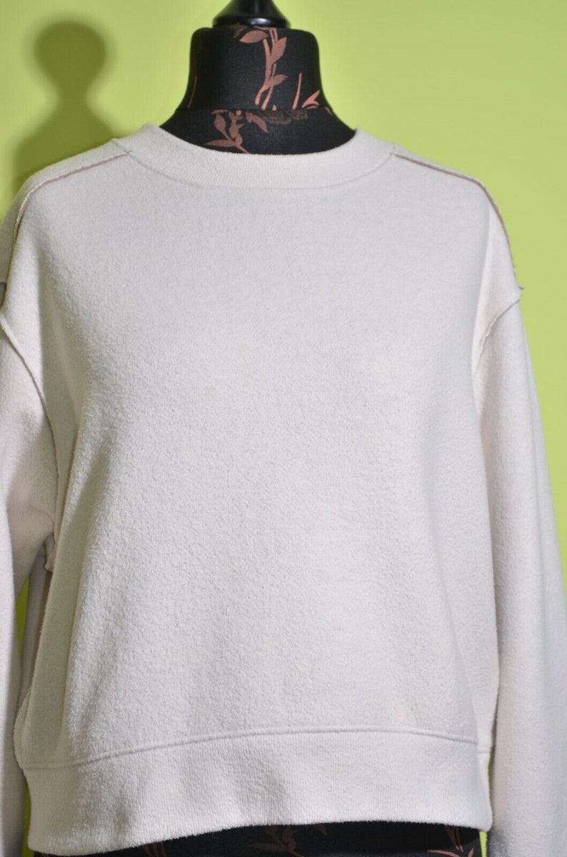 May include: A white, long-sleeved sweatshirt with a crew neck and a slightly cropped hem.