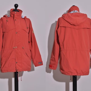May include: A red hooded jacket with a zip fastening and a drawstring waist. The jacket has a logo on the left sleeve.