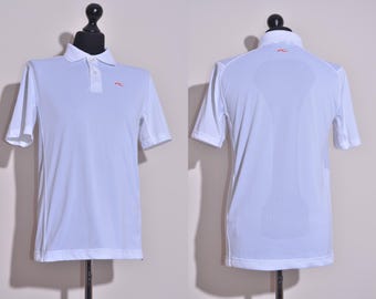 Pode incluir: Camisola polo branca de manga curta com um pequeno logotipo no peito esquerdo e um logotipo maior nas costas.