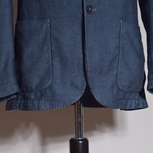 Puede incluir: Chaqueta azul marino con dos bolsillos delanteros y cierre de un solo bot&oacute;n. La chaqueta tiene una tela texturizada y un dise&ntilde;o cl&aacute;sico, adecuada para diversas ocasiones. Las mangas son largas.