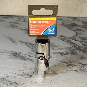 May include: A chrome-plated Crescent universal joint with a 1/2 inch drive. The packaging includes the Crescent logo and the words "Universal Joint" in English, Spanish, and French. The tool is designed for use with sockets.