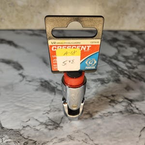 May include: A chrome Crescent socket wrench with a red and black top. The packaging includes the text "1/2 DRIVE/PRISE/CUADRO" and "A-18". A yellow sticker with the number "5.95" is attached to the packaging.