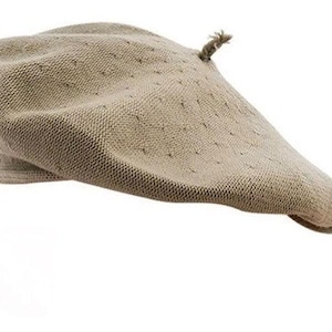 Puede incluir: Un gorro boina beige con un diseño de punto texturizado. El sombrero tiene una corona redondeada y un ala pequeña. Un pequeño detalle decorativo está adherido a la parte superior del sombrero. La boina está hecha de un material suave y transpirable.