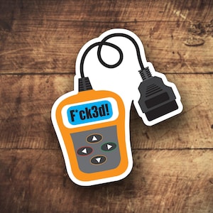 Peut inclure: Un outil de diagnostic automobile jaune et noir avec une bordure blanche et le texte "F*ck3d!" à l'écran. L'outil est doté d'un câble noir.