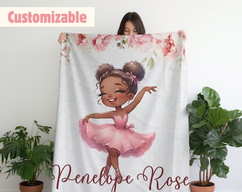 May include: A personalized fleece blanket featuring a cartoon illustration of a young Black ballerina in a pink tutu. The blanket has a floral design and the name "Penelope Rose" is printed in brown text.