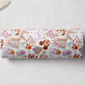 Puede incluir: Tela blanca con un patr&oacute;n repetido de Mickey Mouse, Minnie Mouse y Donald Duck. Los personajes est&aacute;n en un estilo de dibujos animados y est&aacute;n rodeados de detalles coloridos como arco&iacute;ris, estrellas y corazones. La tela tambi&eacute;n presenta el texto "Sophia Ann".