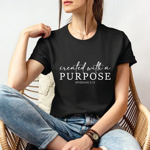 Puede incluir: Camiseta negra con texto blanco que dice "created with a PURPOSE" y "EPHESIANS 2:10".