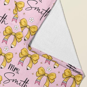 May include: Pink teacher tote bag with a repeating pattern of yellow bows, pencils, and stars. The text "Mrs. Smith" is written in black cursive on the bag.