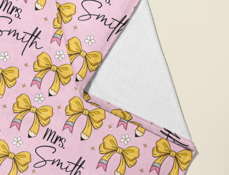 May include: Pink teacher tote bag with a repeating pattern of yellow bows, pencils, and stars. The text "Mrs. Smith" is written in black cursive on the bag.