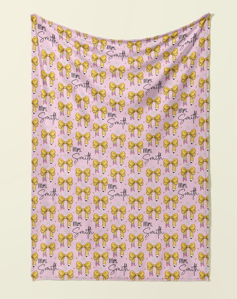 May include: Pink fleece blanket with a repeating pattern of yellow bows and the text "Mrs. Smith" in black script.