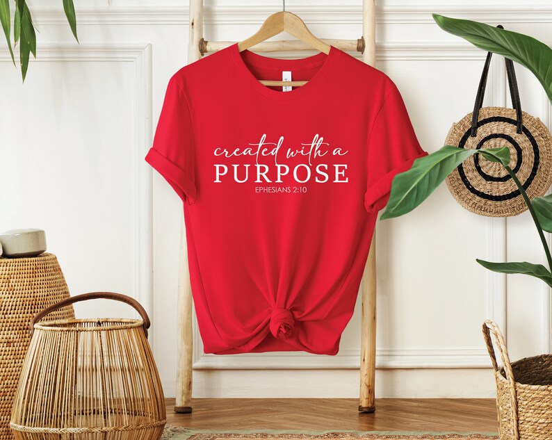 Puede incluir: Camiseta roja con texto blanco que dice "created with a PURPOSE" y "EPHESIANS 2:10".
