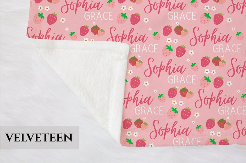 Pode incluir: Cobertor de l&atilde; rosa e branco com um padr&atilde;o repetido de morangos e o nome "Sophia Grace".