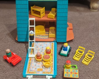 May include: A vintage Fisher-Price Play Family A-Frame dollhouse with accessories. The teal and orange house opens to reveal two floors with yellow furniture. Includes a red car, figures, a green car, and yellow lounge chairs.