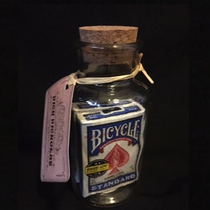 Deux jeux de cartes scellés complets dans une bouteille en verre dont le goulot est plus petit que les objets qu'il contient.