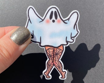 May include: A white ghost wearing a black spiderweb patterned outfit. The ghost is in a playful pose with its arms raised and legs crossed.