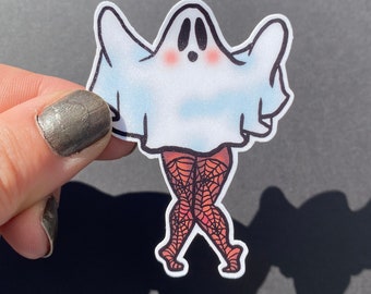 May include: A white ghost wearing a black and orange spiderweb patterned outfit. The ghost is standing with its arms raised and has a surprised expression on its face.